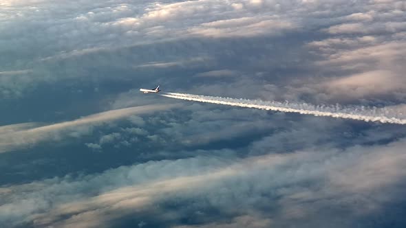 Incredible view from the cockpit of an airplane flying high above the clouds leaving a long white co