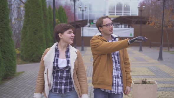 Young Man with a Cyber Prosthetic Arm Walks with His Girlfriend