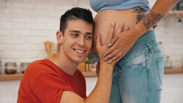 Excited Man Listening to His Baby in His Pregnant Wife's Belly