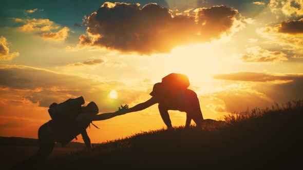 Silhouette of Helping Hand Between Two Climber. Two Hikers on Top of the Mountain