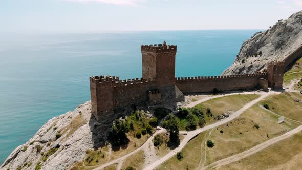 Ancient Medieval Genoese Fortress Tower on Mountain Range Rocks Above Sea Aerial View From Drone to