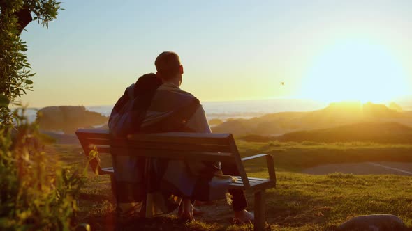 Rear view of couple sitting on bench near beach 4k