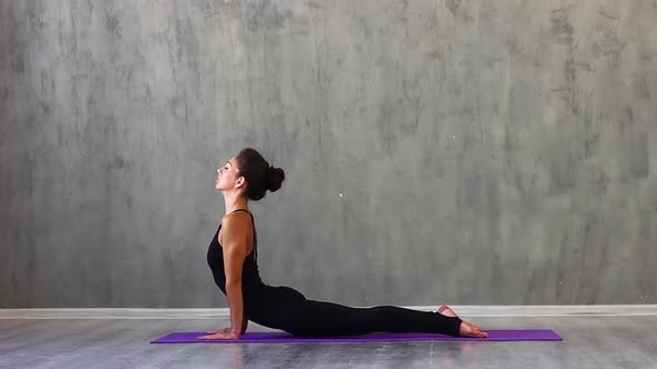 Woman Sports Clothes is Engaged in Yoga on a Purple Sports Mat Studio with Natural Consecration