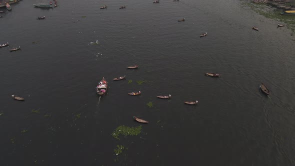 Aerial: black water of the buriganga river with boats and transportations - top down drone tracking