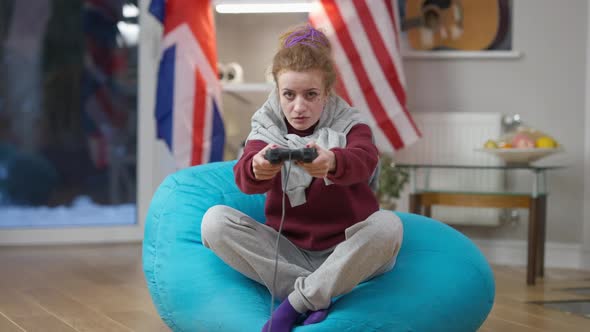 Wide Shot Portrait of Relaxed Carefree Caucasian Woman Using Game Controller Playing Video Game at