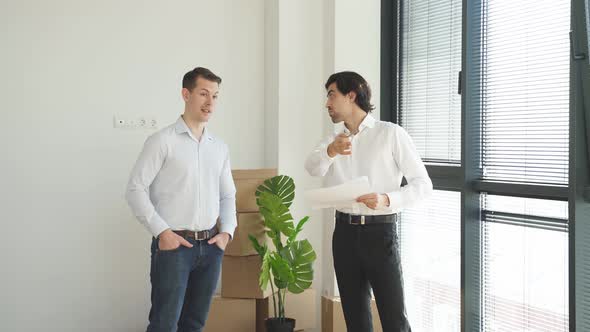 Confident Caucasian Real Estate Agent with House Model on Document is Talking to Clients About