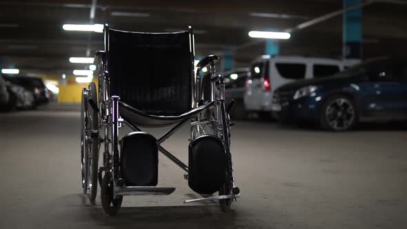 An Empty Wheelchair Stands in the Middle of a Car Park. Wheelchair Is Standing on the Road