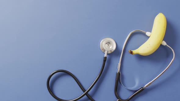 Video of close up of stethoscope with banana on blue background