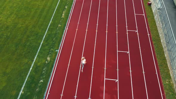 Aerial Drone Shot of a Athlete Running a Short Distance at the Stadium