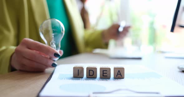 Businesswoman Holds Light Bulb and on Cubes Word Ideas