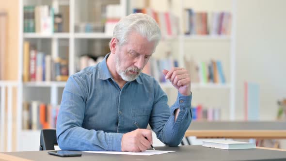 Old Man Writing in Notebook