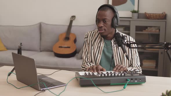 Young African Man Playing Midi Keyboard Synthesizer at Home