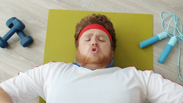 Top View of Funny Overweight Guy Exercising Then Eating Bread Chewing Baguette Lying on Fitness Mat