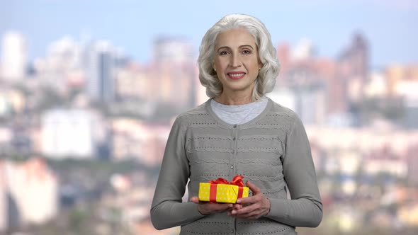 Smiling Mature Woman Showing Gift Box