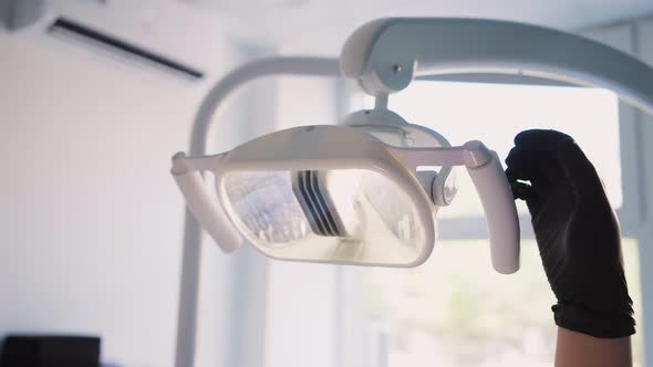 Female doctor dentist in a hospital room prepares a workplace for surgery. Adjusts the medical lamp