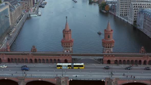 Oberbaum Bridge in Berlin, Germany and Yellow Bus Passing Over Spree River in Daylight, Aerial Tilt