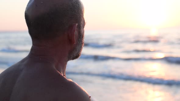 Rear view of senior man enjoying sunset at beach