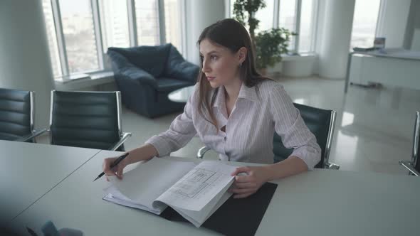 Young Employee Working at the Table in the Office. Attractive Business Woman Looking Through