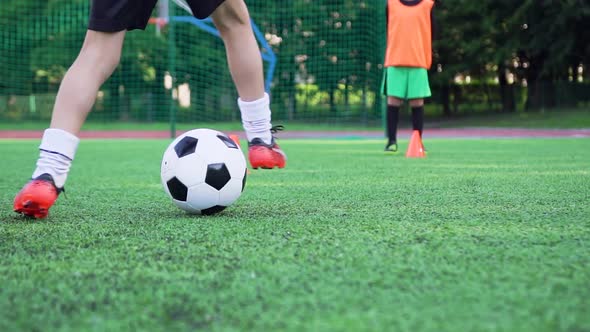 Boy's Feet in Football Shoes which Working Out the Kick with Ball During Training Day