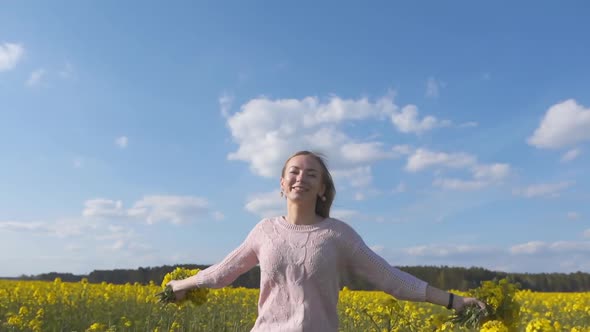 A Happy Girl Runs Among a Rapeseed Field on a Warm Spring Day. Slow Motion Mode alt