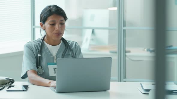 Hispanic Female Doctor Working on Laptop in Clinic