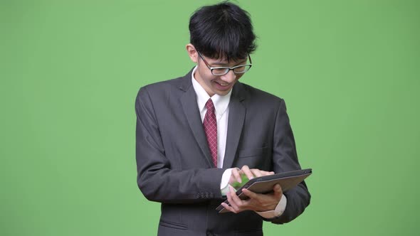 Young Happy Asian Businessman Smiling While Using Digital Tablet