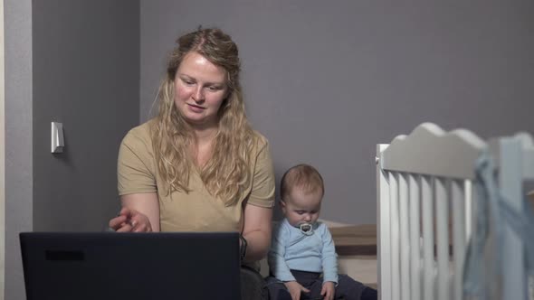 Mom Works at Home with a Laptop, Being Distracted by the Child.