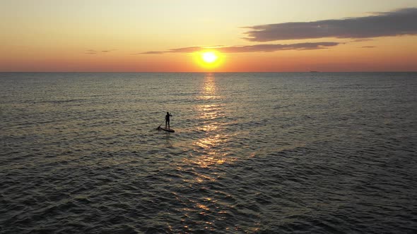 Young woman on a stand up paddle board exercising at sunset. Stand Up Paddle Board 