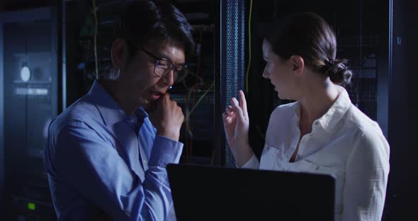 Diverse female and male it technicians using laptop checking computer server