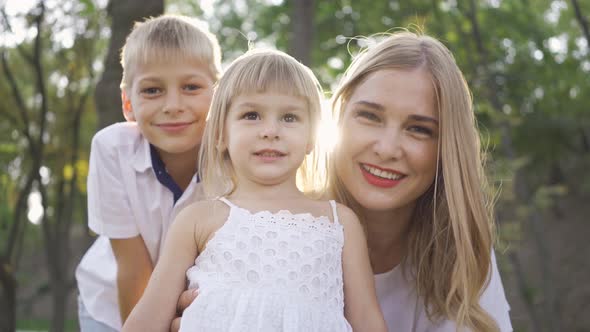 Pretty Blond Woman and Her Two Kids Looking at the Camera Smiling