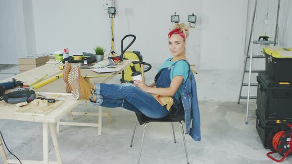 Woman Resting with Smartphone at Carpenter Workbench