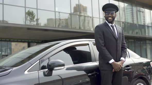 Smiling African-American Taxi Service Driver Expecting Client Near Luxury Car