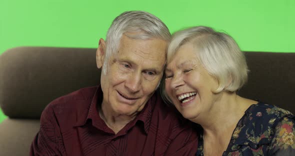 Senior Aged Man and Woman Sitting Together on a Sofa and Smiles. Chroma Key