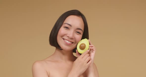 Portrait of Asian Woman Stroking Avocado and Face Closeup