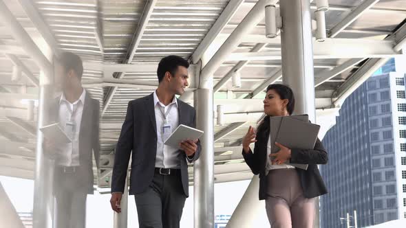 Businesswoman carrying folders walking outside an office discussing plans