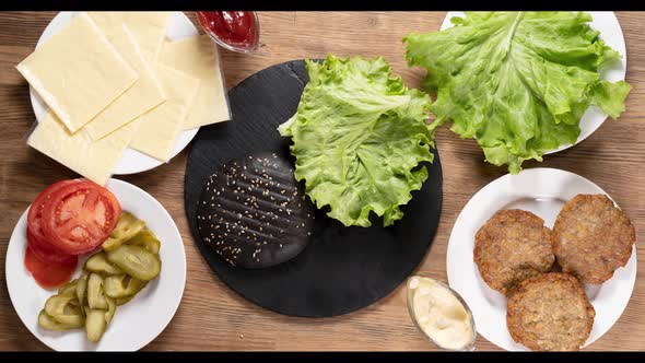 The Hamburger Ingredients That Make Up the Delicious Burger are Top View Slow Motion Black Bun