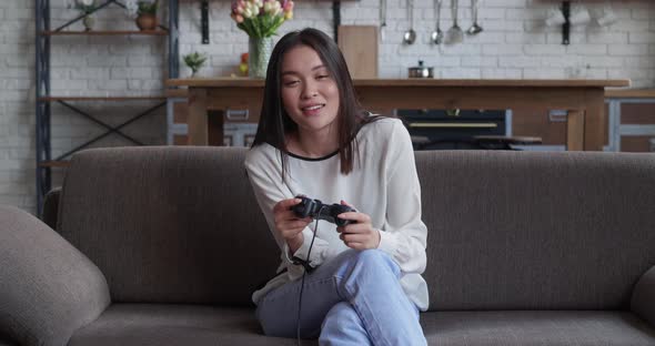 Focused Young Asian Woman Playing Video Game Joystic Controller Playing Video Games at Home