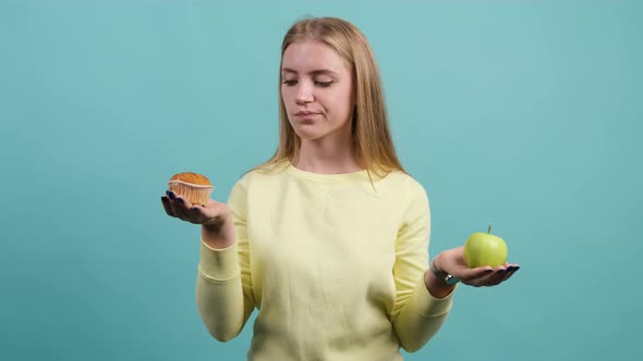 Young Woman Choosing Between Apple and Cupcake, the Girl Is Choose Cupcake