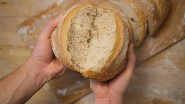 Men's hands break up freshly baked bread in a bakery