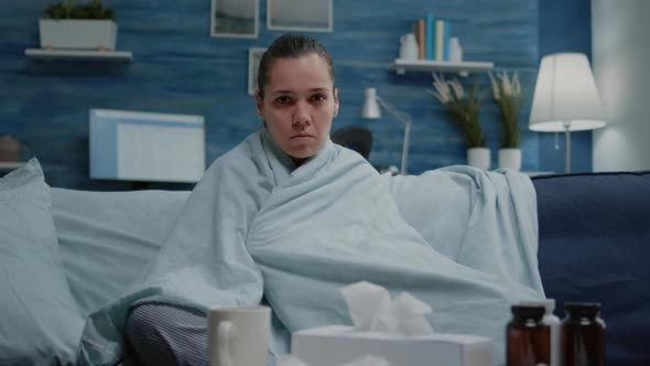 Woman with Virus Infection Sitting in Blanket Looking at Camera