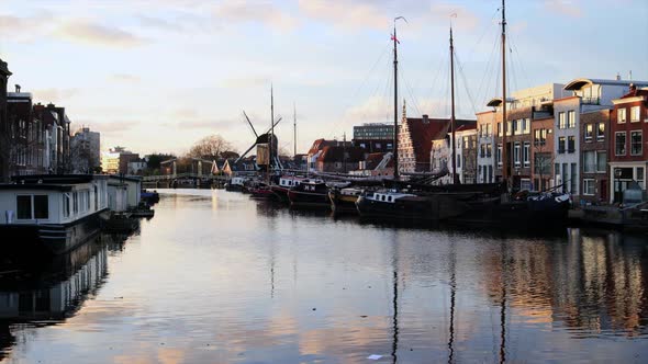 Distant View Of Molen De Put Windmill By The Canal Water In Leiden, Netherlands On A Sunset - time l