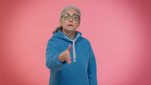 Friendly Senior Woman Outstretching Hand to Camera Offering Handshake Greeting with Kind Smile