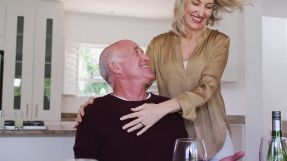 Caucasian senior couple sitting by a table drinking wine eating dinner and hugging