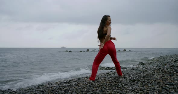 Sexy Young Woman Is Warming Her Muscles During Morning Workout on Sea Shore