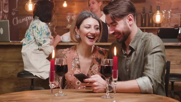 Beautiful Couple Laughing Over Some Pictures on the Smartphone