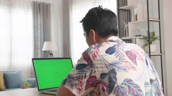 Asian Man Using Laptop Computer With Green Screen At Home