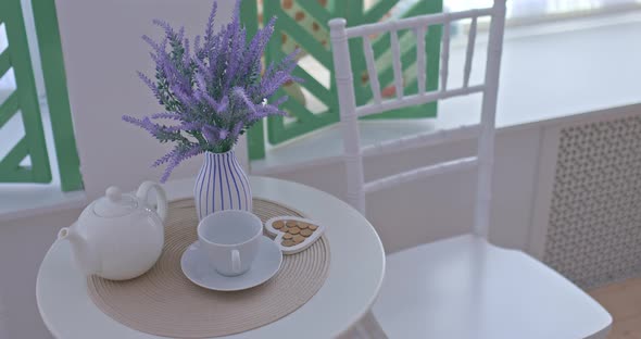 Bouquet of Blue Lavender Stands in a Vase on a Round Table a White Cup and a Teapot in the Interior