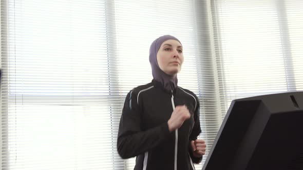 Athlete Girl in Hijab on a Running Simulator