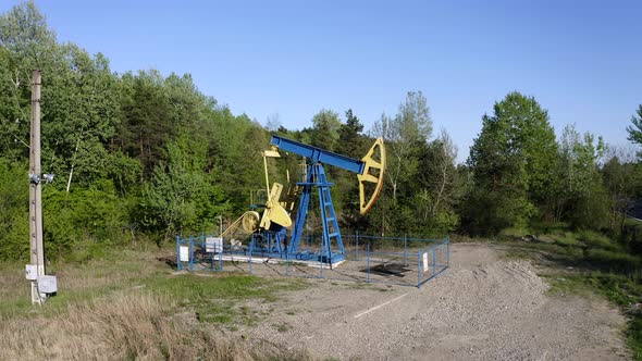 Oil Pump Equipment At Work On The Landscape Surrounded With Green Forest Near Campina, Romania. wide
