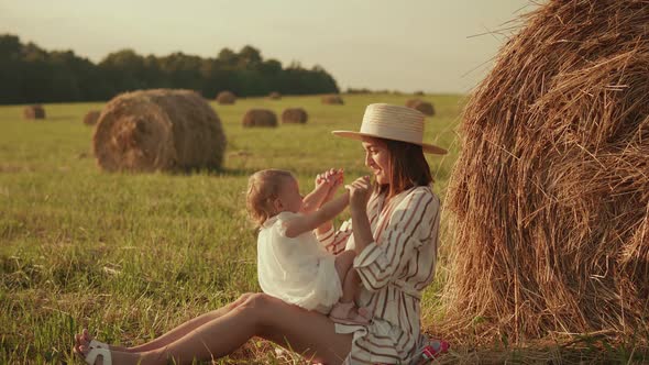 Young mother playing with her baby in the field